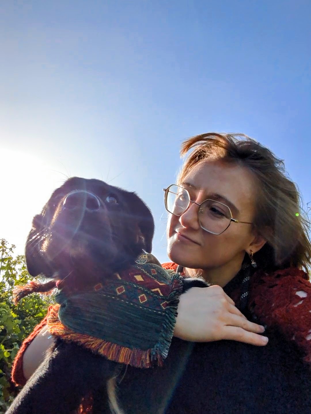 Chibi outdoors on a bright day, holding her dog Odi